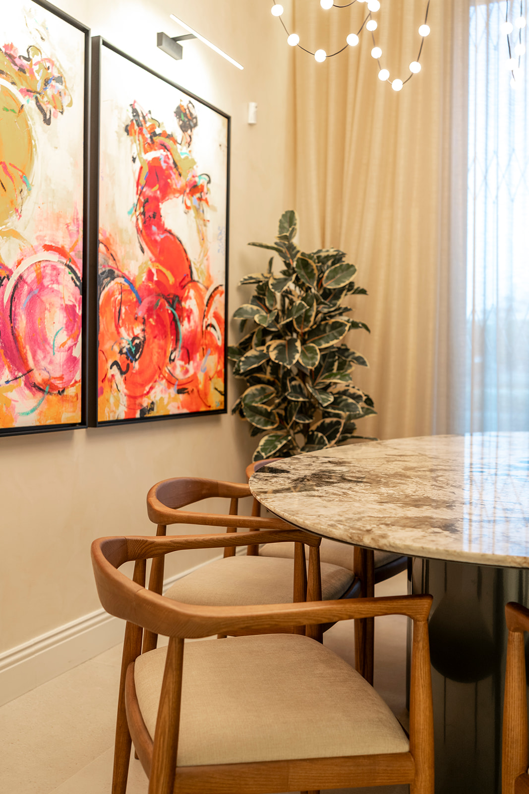 Sillas de madera y mesa de mármol junto a las obras de arte del comedor