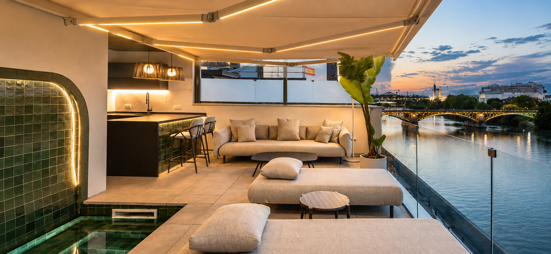 Salón exterior de la terraza de CasaKary al atardecer, con el puente de Triana al fondo